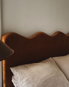 a brown headboard with two pillows and a lamp on the nightstand next to it