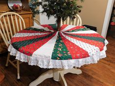 a christmas tree sits on top of a table covered with red, green and white fabric