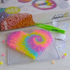 the beaded heart is sitting next to some crafting supplies on top of a table