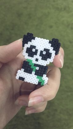 a person holding a small pixelated panda bear in their left hand and wearing a green shirt