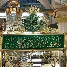 a green and gold sign hanging from the side of a building in arabic writing on it