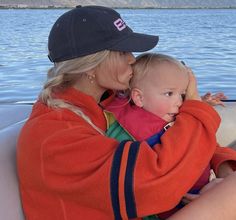 a woman holding a baby in her arms while sitting on the back of a boat