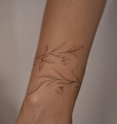 a woman's arm with a tattoo on it that has flowers and leaves drawn on it