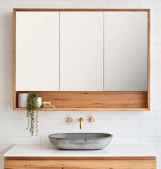 a bathroom with a sink, mirror and wooden cabinet in the corner on the wall