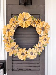 a wreath with yellow flowers hanging on the front door to decorate it for fall or halloween