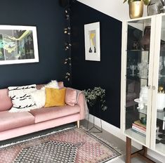 a living room with black walls and pink couch in the corner, white rug on the floor