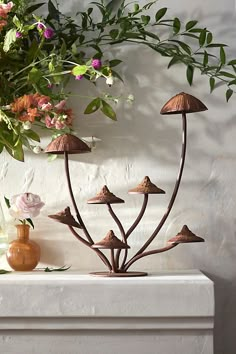 a vase filled with lots of flowers sitting on top of a white table next to a plant