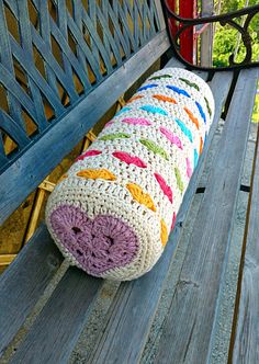 a crocheted pillow sitting on top of a wooden bench