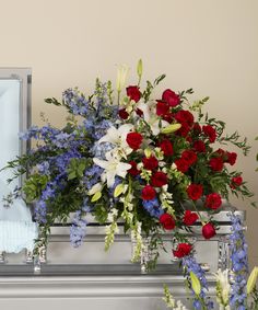 rose, lily, delphinium, casket, funeral, memorial, sympathy A large patriotic spray of red roses, white lilies, and blue delphinium - a touching tribute to the casket. White Casket Spray, White Casket, Sympathy Floral, Poinsettia Care, Casket Flowers, Casket Spray, Walter Knoll, Casket Sprays, Blue Delphinium