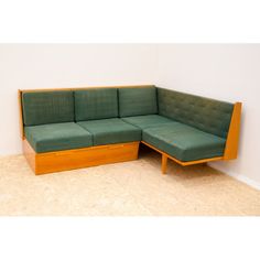 a green couch sitting on top of a hard wood floor next to a white wall