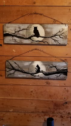 two wooden signs hanging on the side of a wall with trees and cats in it