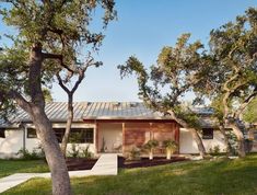 a house with trees in front of it and grass on the ground next to it