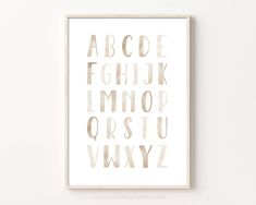 a white framed print with the alphabet in gold foil on it's sides and bottom