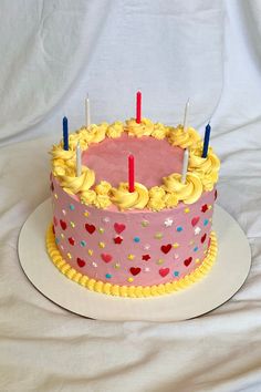 a pink cake with yellow frosting and candles