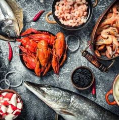 lobsters, clams, and other seafood are arranged on a black table top