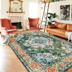 a living room filled with furniture and a rug on top of a hard wood floor