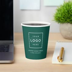 a coffee cup sitting on top of a desk next to a laptop