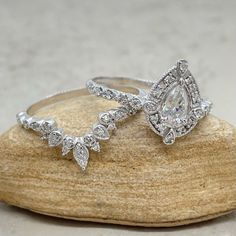 two wedding rings sitting on top of a rock next to each other with diamond accents