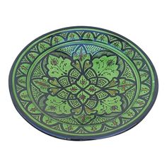 a green and blue plate with an intricate design on the front, sitting on a white surface