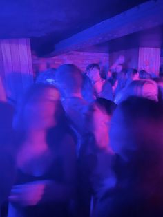 a group of people standing around in a room with blue lights on the walls and floor