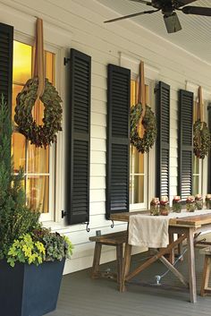 a screen shot of a porch with black shutters and potted plants on it