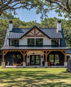 a large house with a metal roof in the middle of a grassy area surrounded by trees