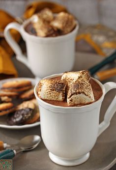 two cups filled with hot chocolate and marshmallows on top of a table