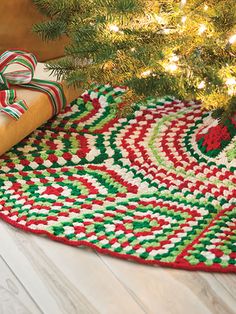 a green and red rug next to a christmas tree with presents on the floor under it