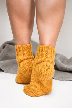 "Elegant hand-knit cable slipper socks that will perfectly suit your off days when lounging at home wrapped in one of our blanket shawls sipping your favorite beverage. Details: * Designed and made by us in our studio in Riga, Latvia using traditional techniques and thoughtfully sourced materials; * Hand knit from luxurious Peruvian Highland wool; * Suited for women and men; * Can be worn all-year-round, and requires little maintenance; * Will make you instantaneously warm and cozy; * Does not h Fall Slippers, Winter Leg Warmers, Cable Socks, Wool Bed, Bed Socks, Blanket Shawl, Riga Latvia, Wool Slippers, Light Knit