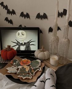 a laptop computer sitting on top of a wooden table next to halloween decorations and candles