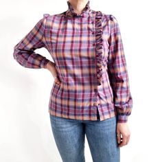 Stunning vintage blouse in purple check pattern with a filly collar and side detail. It has a simple shape, slightly puffed, long sleeves and small buttons fastening on one side. It is made from lightweight cotton fabric. An amazing statement blouse for tucking into trousers and skirts. No make label. No material label, cotton. No size label, would fit Small to Medium. Measurements when laid flat are: Shoulder to shoulder: 40cm Pit to pit: 50cm Waist: 45cm Hemline: 51cm Length: 63cm  Sleeve leng Plaid Long Sleeve Blouse For Office, Plaid Long Sleeve Tops For Office, Plaid Long Sleeve Blouse With Ruffles, Vintage Shirt For Office In Fall, Vintage Office Shirt For Fall, Vintage Fall Office Shirt, Vintage Purple Tops With Button Closure, Fitted Plaid Blouse With Buttons, Plaid Fitted Blouse For Work