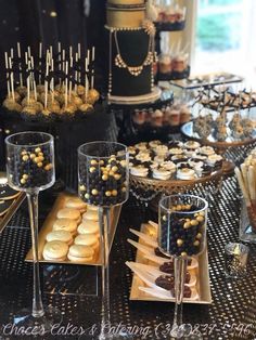 a table topped with desserts and cupcakes next to wine glasses filled with candy