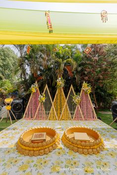 an elaborately decorated bed in the middle of a lawn with yellow and pink decorations