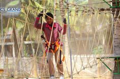 a man walking across a rope bridge with ropes attached to the sides and two hands on each side