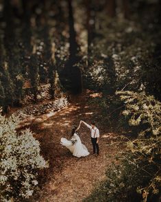 a bride and groom dancing in the woods