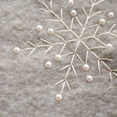 a snowflake made out of white pearls on top of a gray surface with other beads