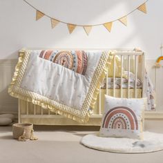 a baby's room with a crib, blanket and pillows on the floor