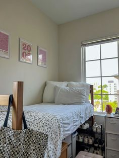 a bed sitting in a bedroom next to a window with pictures on the wall above it