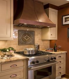 a stove top oven sitting inside of a kitchen next to a wall with pictures on it