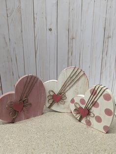 three wooden hearts with bows on them sitting next to each other in front of a white wall