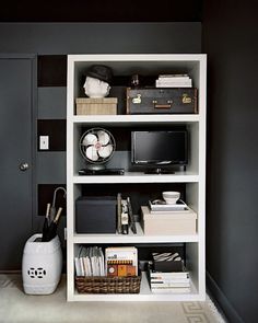 a bookshelf with various items on it in a room that is painted black and white