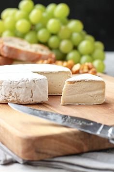 cheese and grapes are on a cutting board