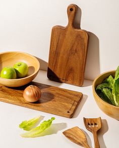 a wooden bowl filled with lettuce next to two bowls of fruit and vegetables