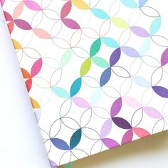 an open notebook with colorful circles on the front and back cover, sitting on a white surface