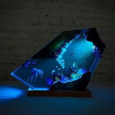 a glass sculpture with an underwater scene in the center and blue light coming from behind it