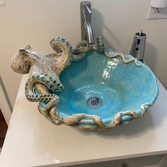 a bathroom sink with an octopus design on the bowl and under running faucet