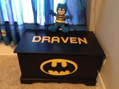 a batman toy box with the word drawn on it and a stuffed animal sitting on top