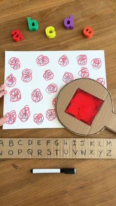 a child's hand holding a rubber stamp over a piece of paper with letters on it