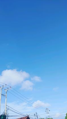 an airplane is flying high in the sky above some power lines and buildings on a sunny day