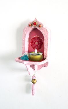 a pink shelf with a red fan on it and some decorations hanging from the wall